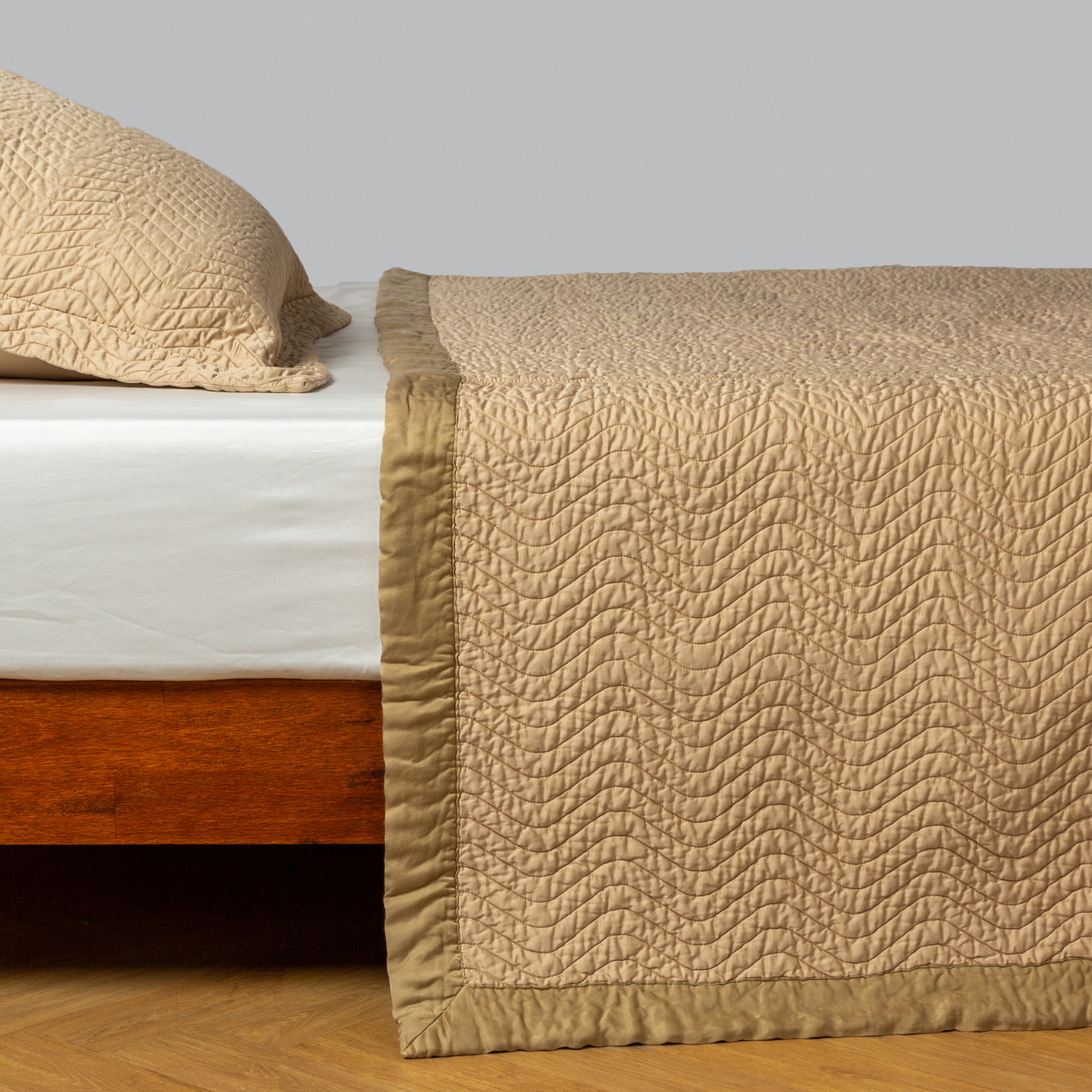 Honeycomb: quilted cotton sateen coverlet with matching sham on a winter white fitted sheet - side view.