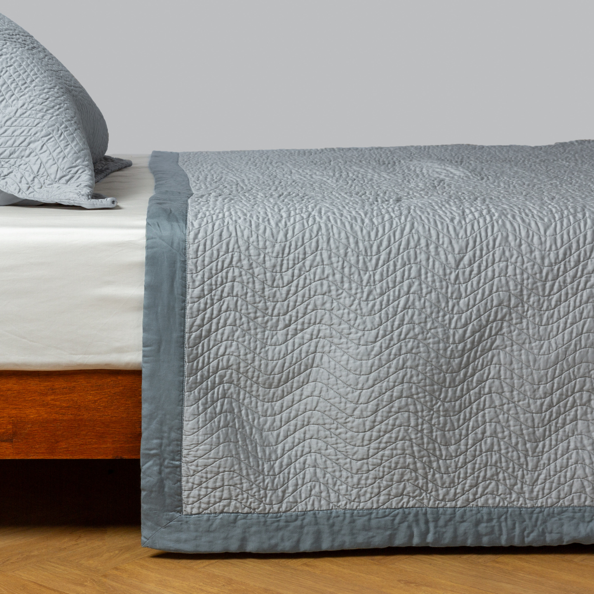 Mineral: quilted cotton sateen coverlet with matching sham on a winter white fitted sheet - side view.