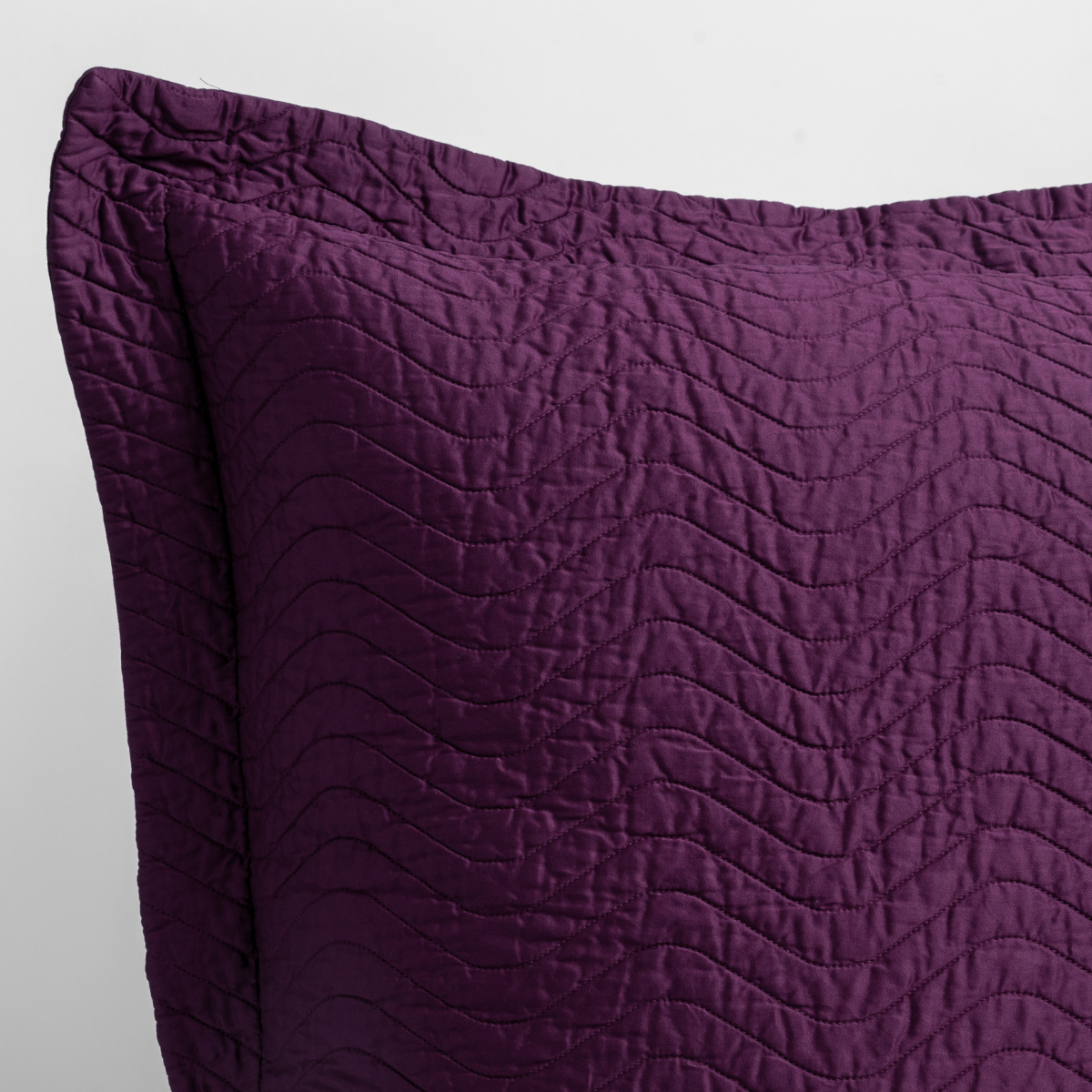 Fig: close up of the corner of a quilted cotton sateen pillow sham - shot against a white background.