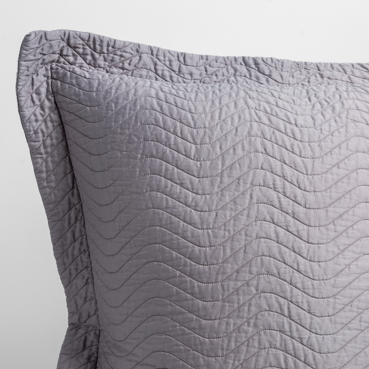 French Lavender: close up of the corner of a quilted cotton sateen pillow sham - shot against a white background.