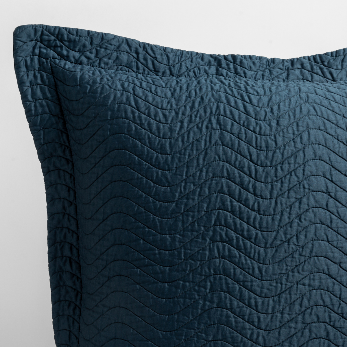 Midnight: close up of the corner of a quilted cotton sateen pillow sham - shot against a white background.