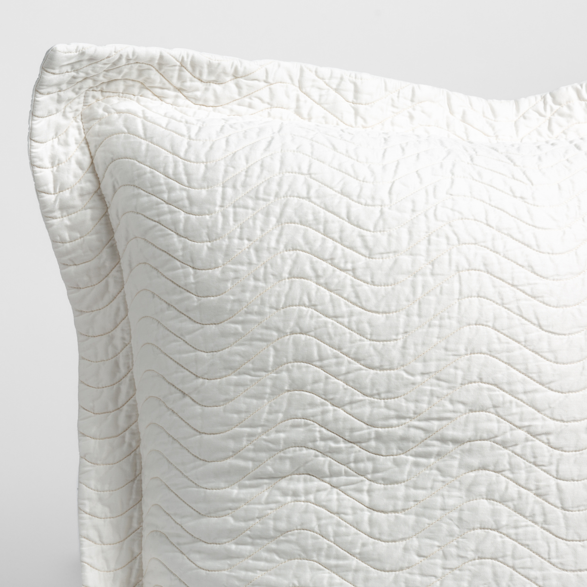 Winter White: a close up of a pillow corner showing the flange framing quilted cotton sateen shot against a white background.