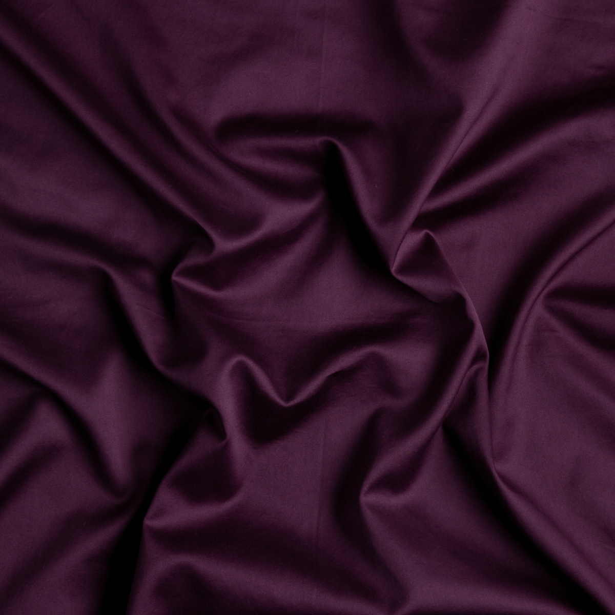 Fig: A close up of cotton sateen fabric in fig, a richly saturated purple-garnet.