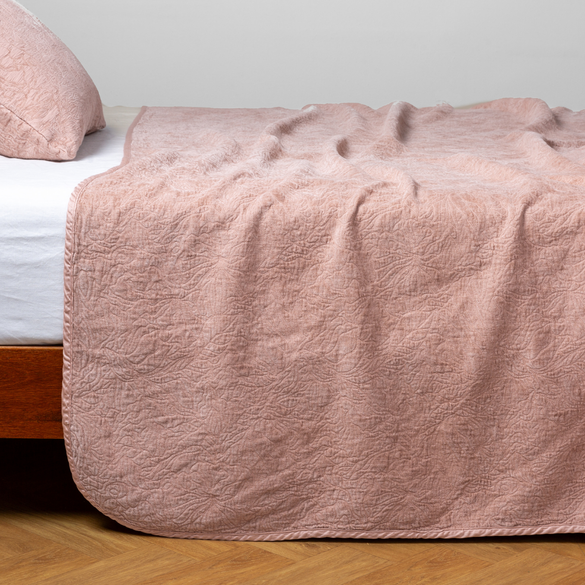 Rouge: side view of the chenille jacquard side of a bedspread with the cotton jacquard side showing on the matching sham — shown with a winter white fitted sheet.