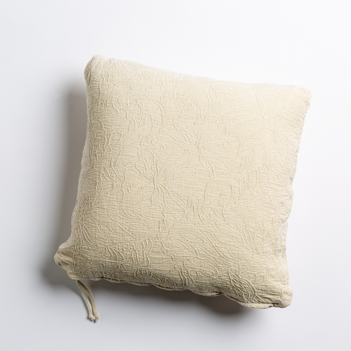 Parchment: cotton jacquard side of a georgia square cushion shown from overhead against a white background.