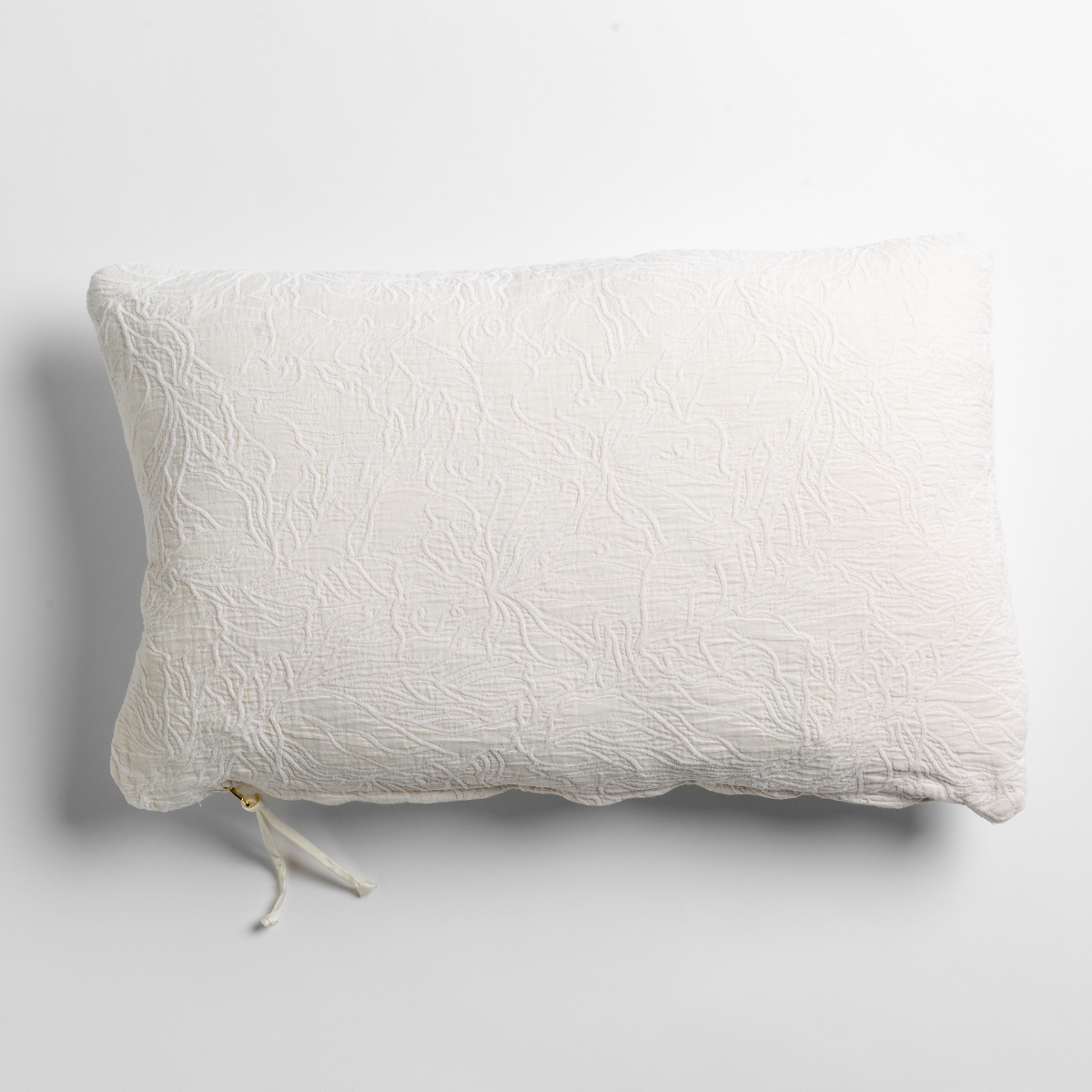 Winter White: cotton jacquard side of a rectangle throw pillow shown from overhead against a white background.