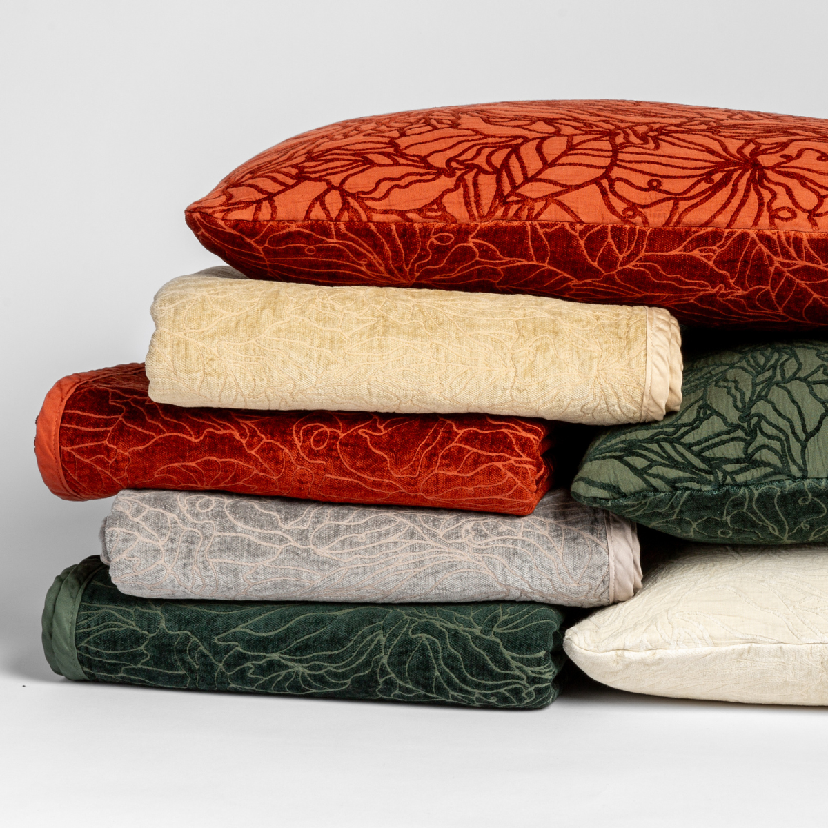 : A cluster of three Georgia shams displayed on their cotton jacquard side and four Georgia blankets displayed on their chenille jacquard sides, all against a white background