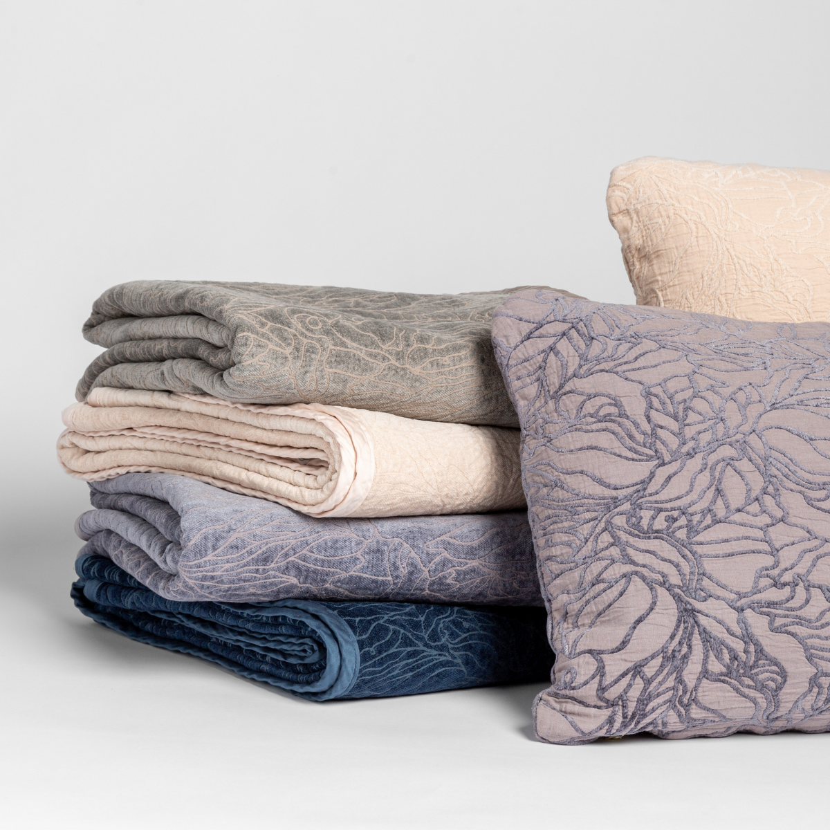 a cluster of georgia throw blankets and pillows in multiple colors show off the pattern in both chenille and cotton jacquards.