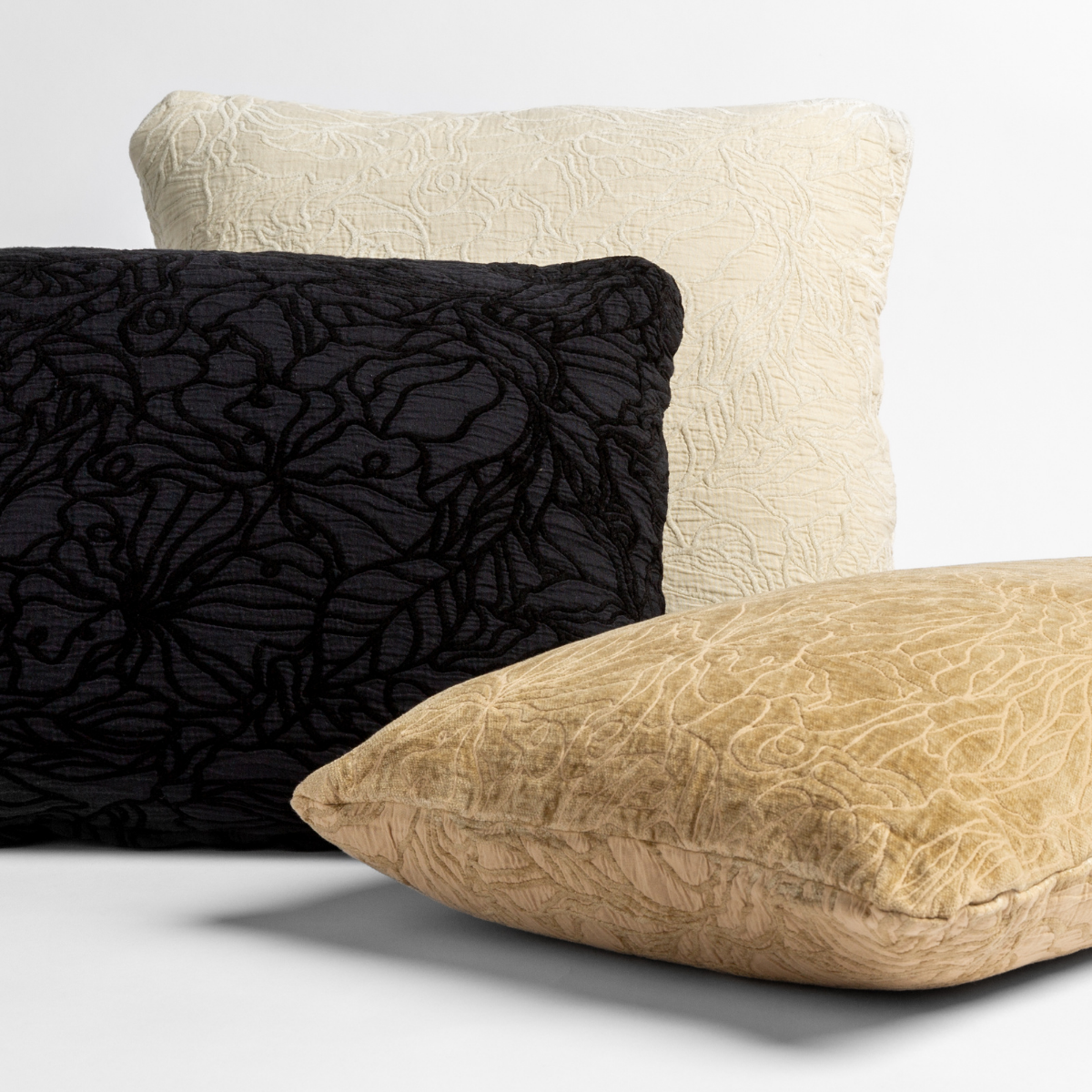 three throw pillows show the chenille and cotton jacquard faces of the reversible pillows in different colors against a white background.