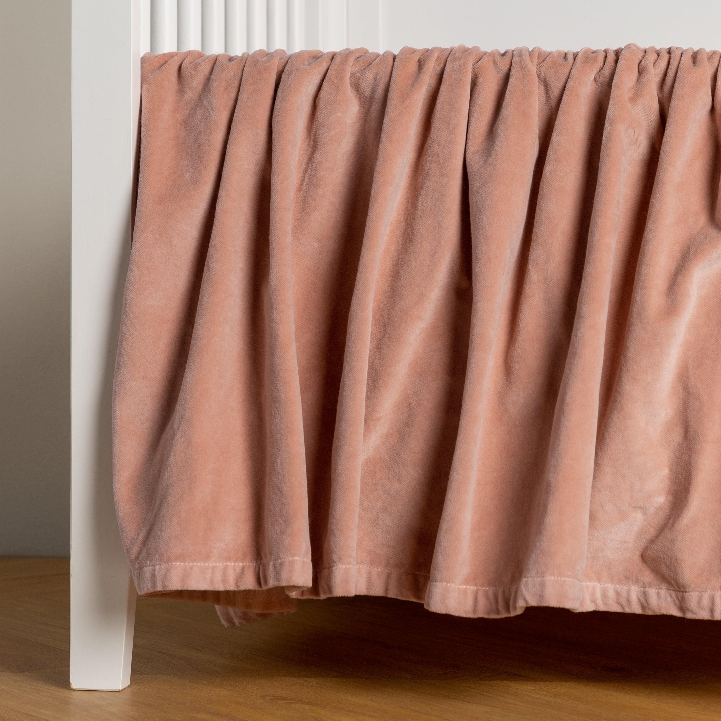 Rouge: cotton velvet crib skirt shown on a white crib .