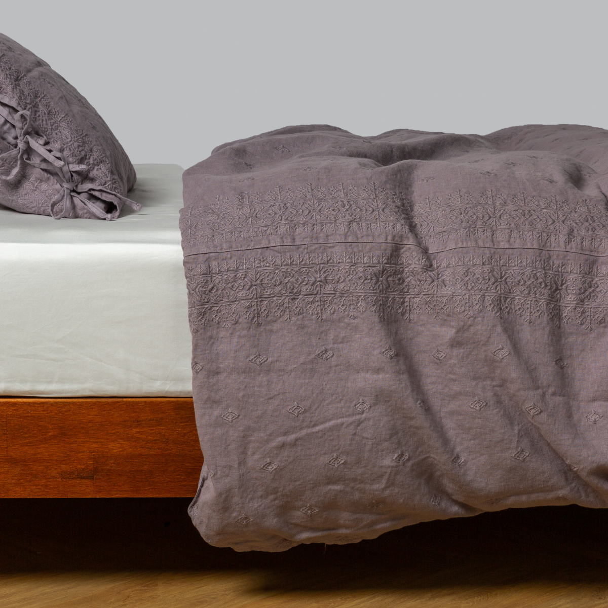 embroidered midweight linen duvet cover with matching sham with side ties on a bed with a winter white fitted sheet - side view.