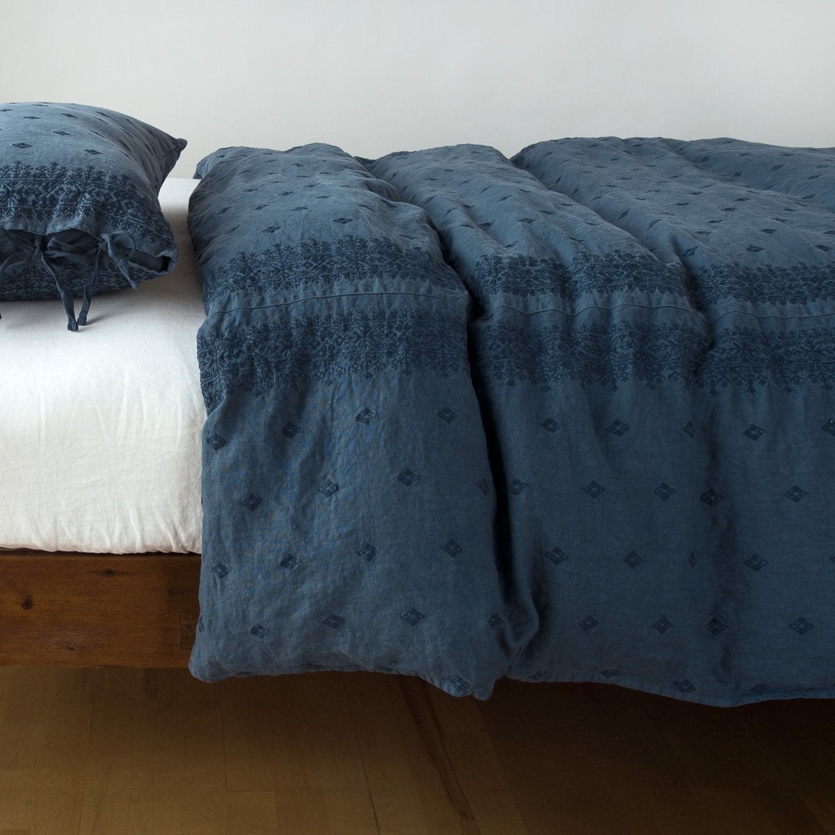 Midnight: lightly rumpled duvet cover on a monochromatic bed against a white background - side view.