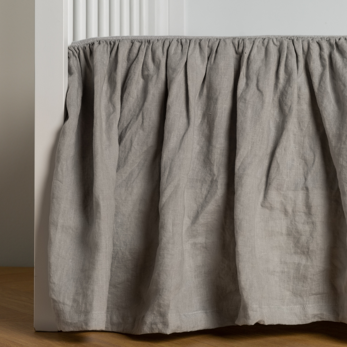 Mineral: crib skirt shown on a white crib with no mattress against a white wall and medium wood flooring.
