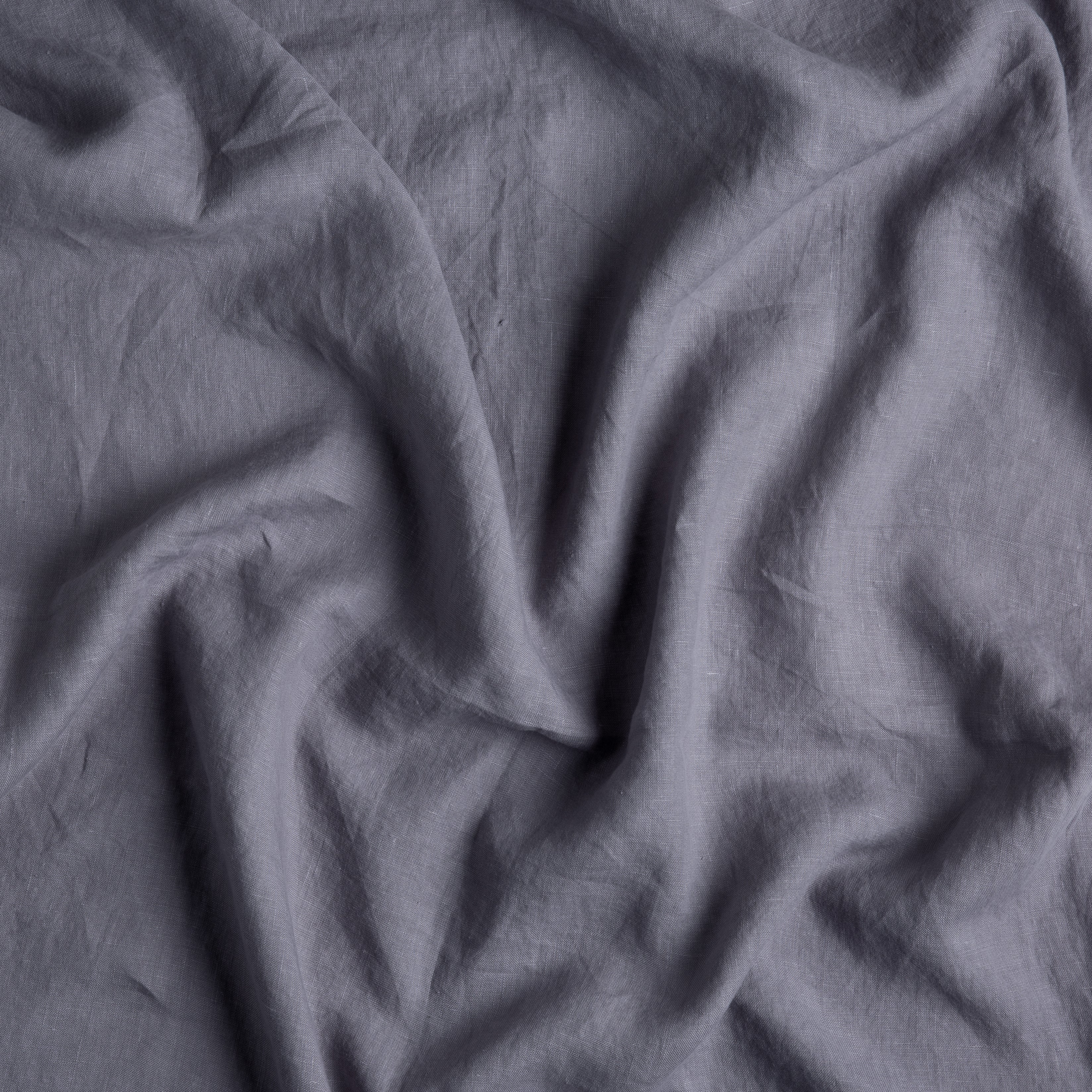A close up of rumpled linen fabric in french lavender, a neutral lavender tone.