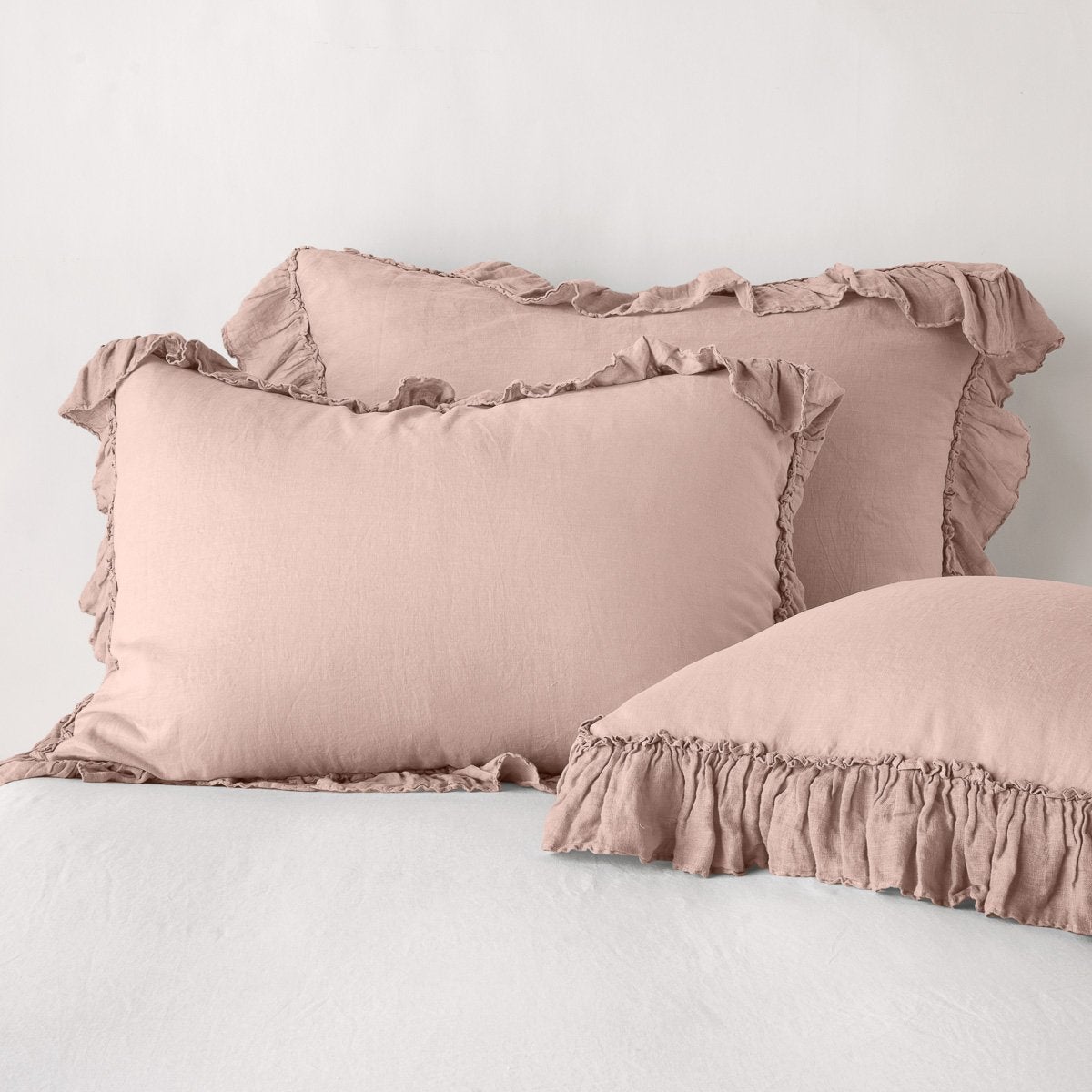 Rouge: two shams leaning upright and one laying flat at an angle in the foreground, against a blank background.