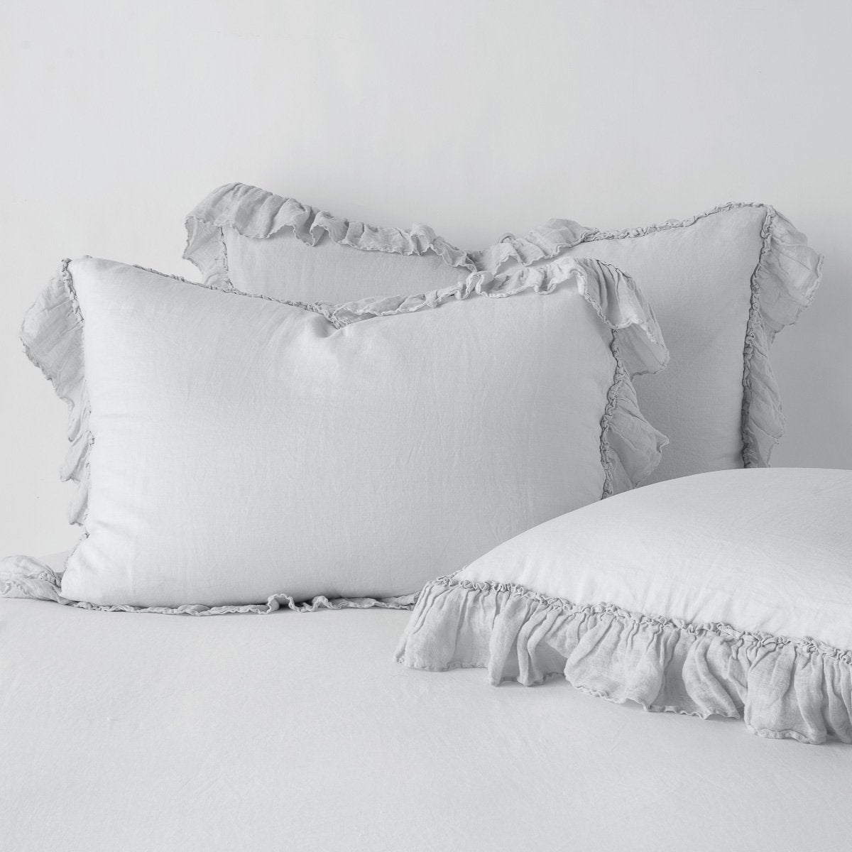 Sterling: two shams leaning upright and one laying flat at an angle in the foreground, against a blank background.