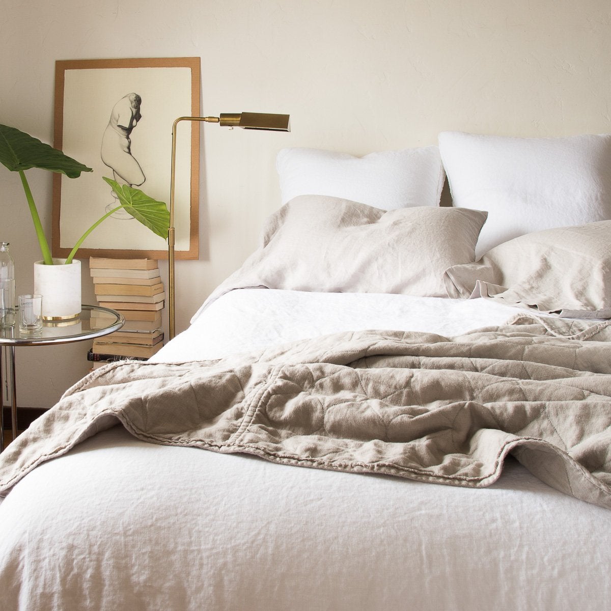 : A soothing, neutral bed with linen pillow cases and linen quilted coverlet in fog over white linen duvet and shams - end of bed view.