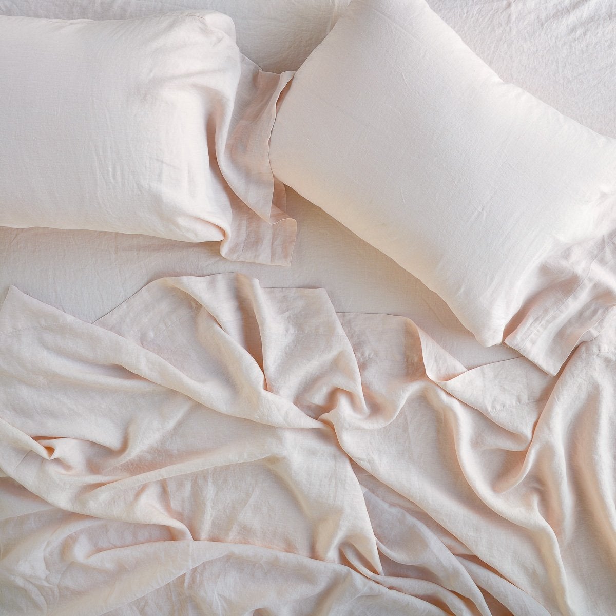 Pearl: sleeping pillows laid flat on rumpled matching sheeting - overhead view.