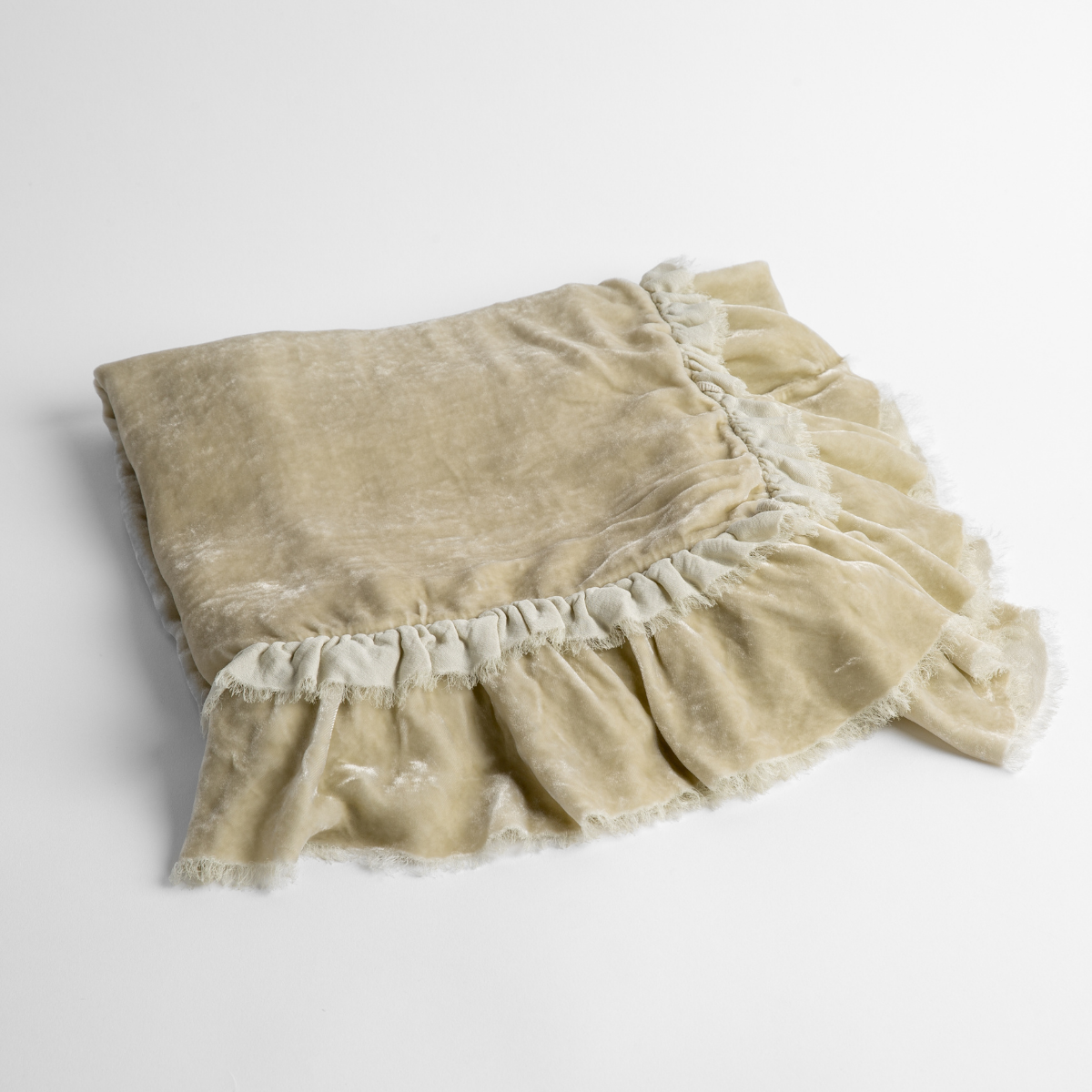 Parchment: an overhead shot of a folded silk velvet baby blanket with a raw-edged eyelash ruffle detail.