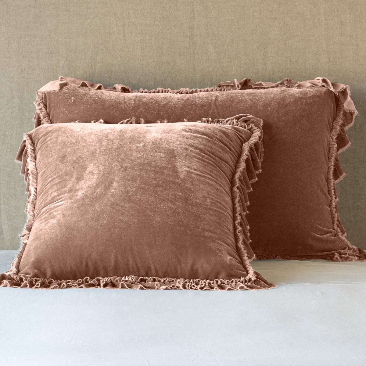 Rouge: shams leaning upright on white sheets against a neutral headboard.