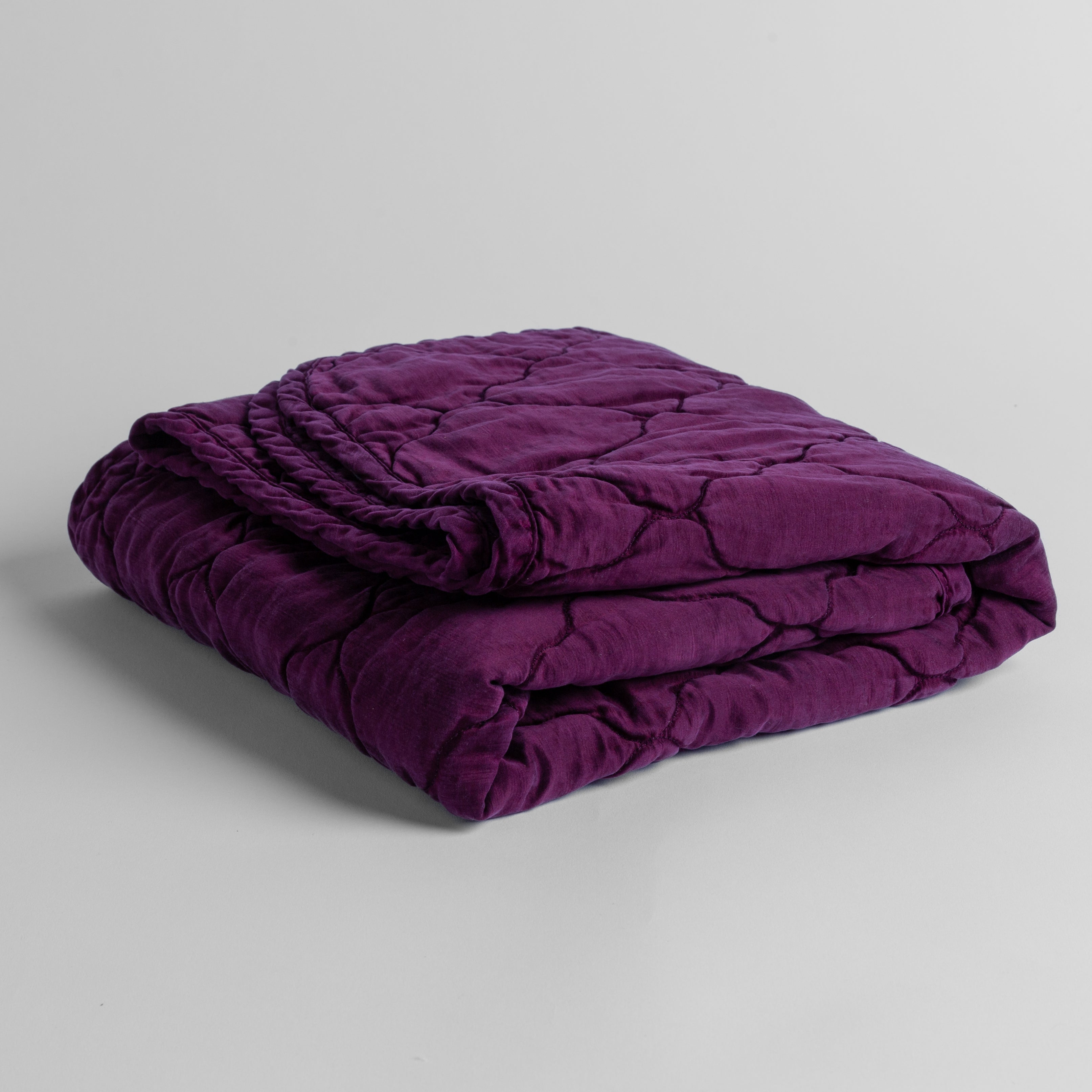 Fig: quilted charmeuse blanket folded and shown against a white background from a slight overhead angle.