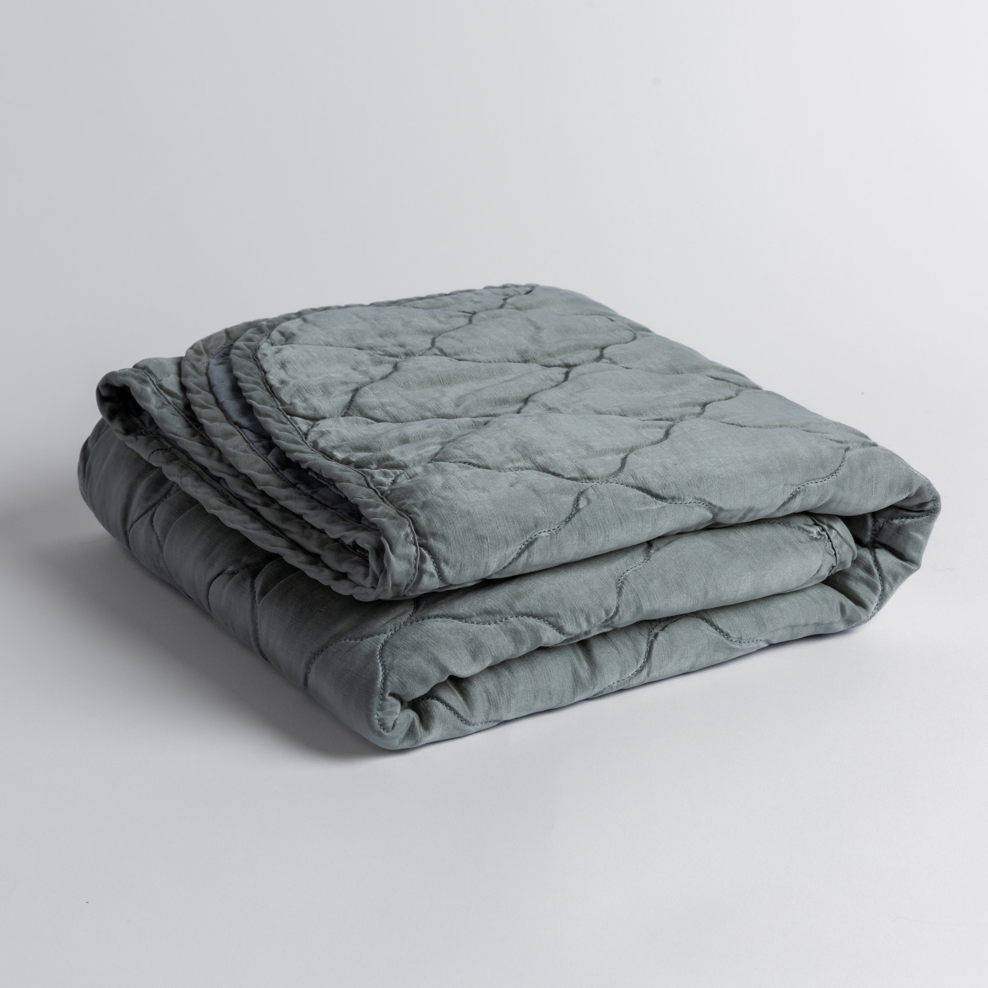 Mineral: quilted charmeuse blanket folded and shown against a white background from a slight overhead angle.