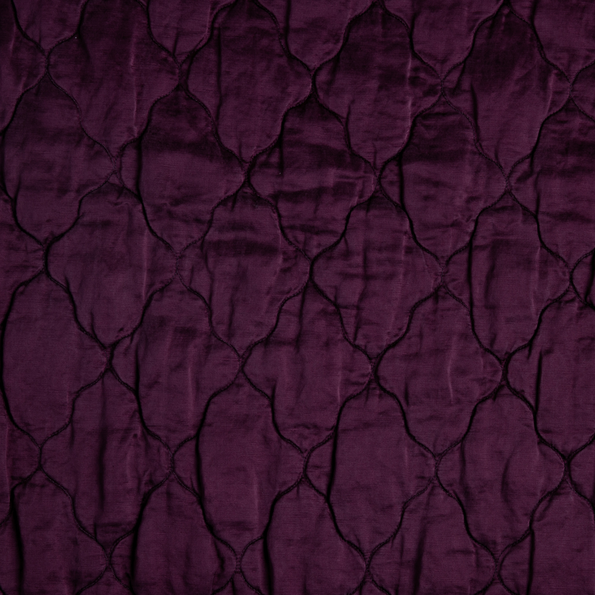 Fig: A close up of quilted charmeuse fabric in fig, a richly saturated purple-garnet.