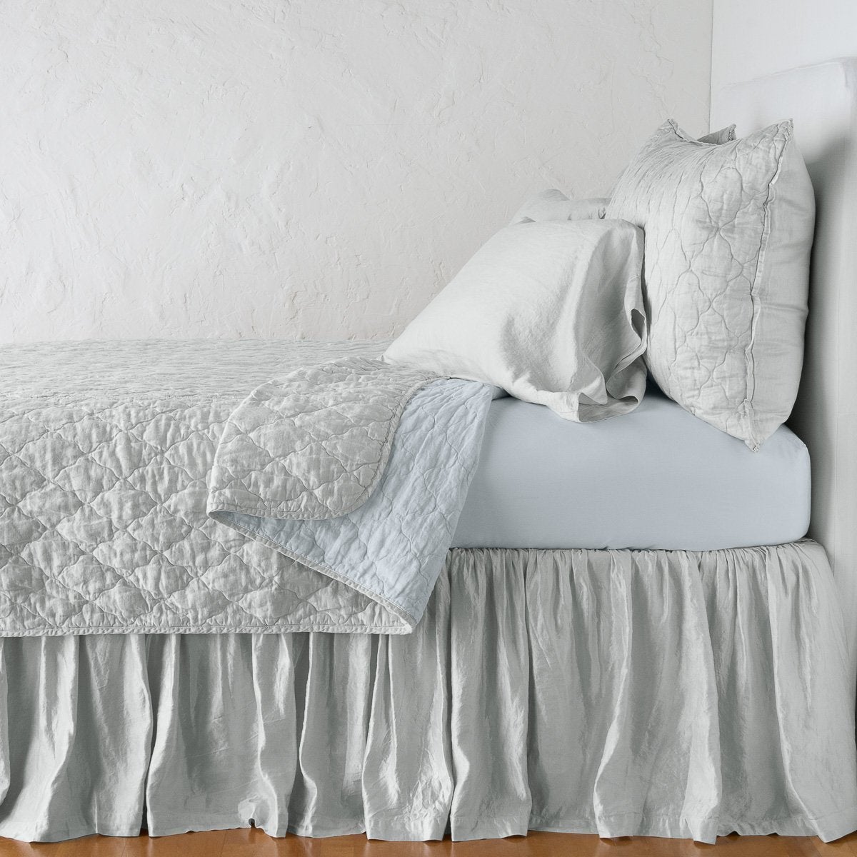 Cloud: shams with a matching coverlet pulled back over monochromatic sheeting - side view.