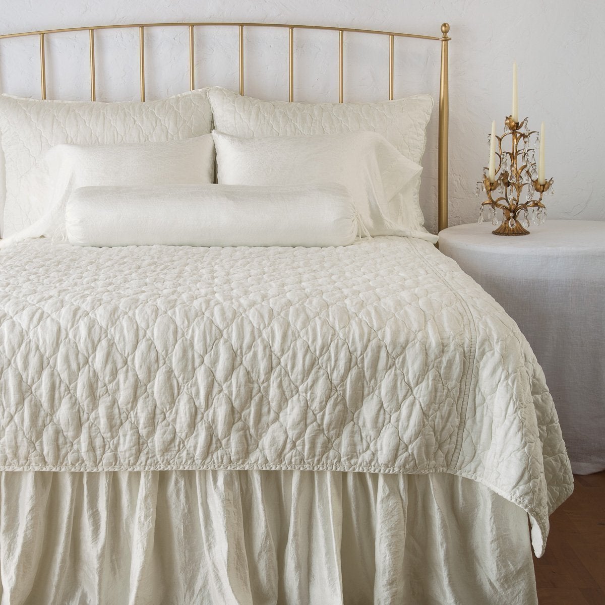 Parchment: shams on a shining, monochromatic bed with matching coverlet - end of bed view.