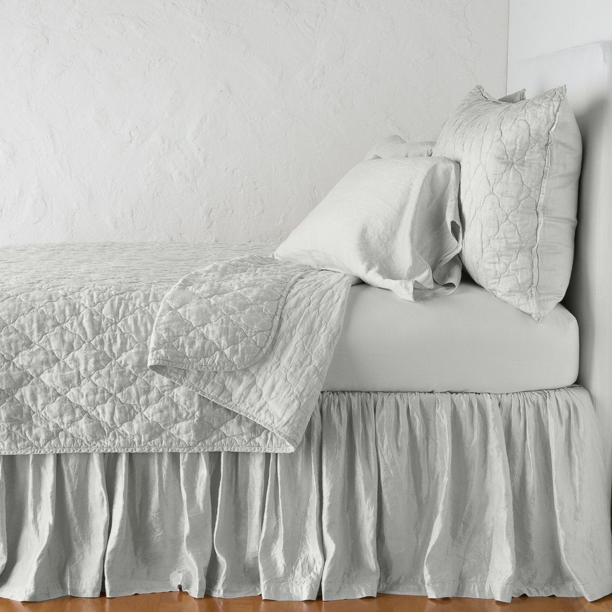 Sterling: shams with a matching coverlet pulled back over monochromatic sheeting - side view.