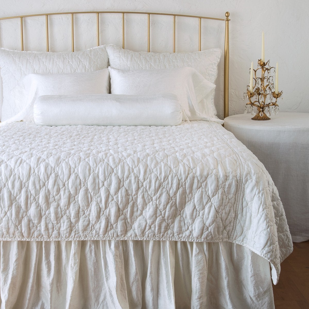Winter White: shams on a shining, monochromatic bed with matching coverlet - end of bed view.