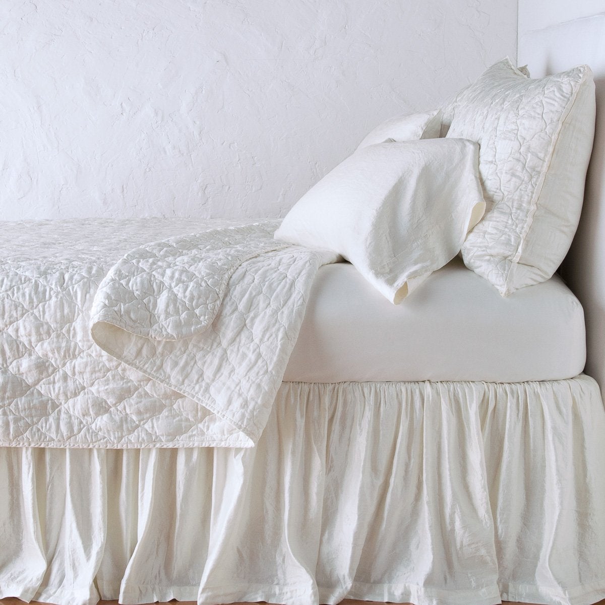 Winter White: shams with a matching coverlet pulled back over monochromatic sheeting - side view.