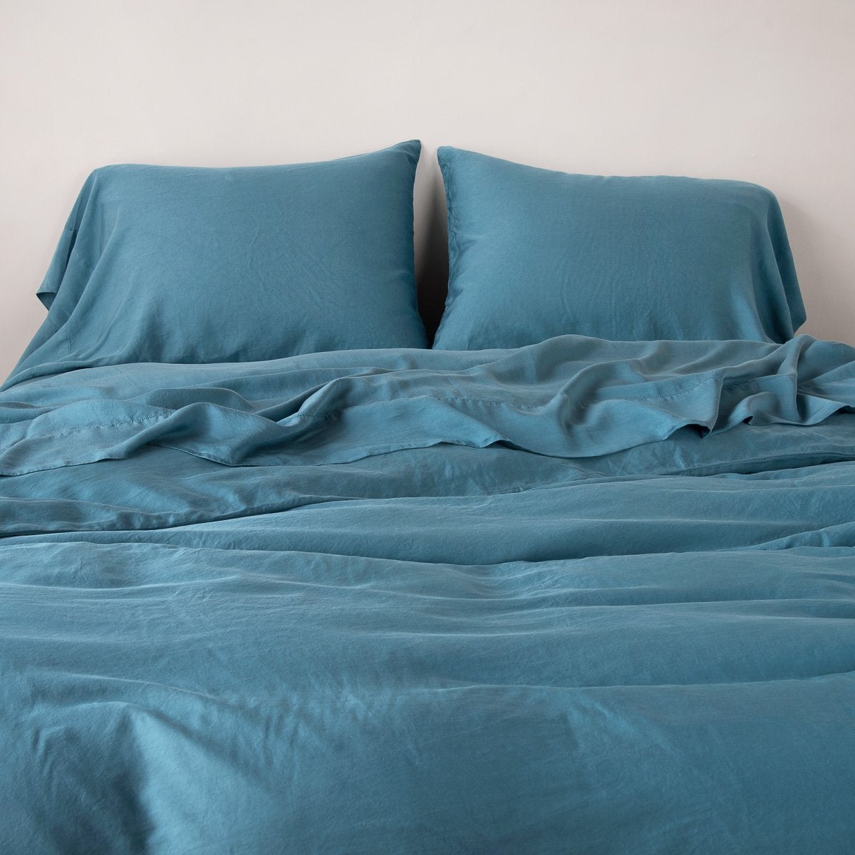 : Madera Luxe duvet cover with matching sleeping pillows and sheeting against a white background - cenote, end of bed view.