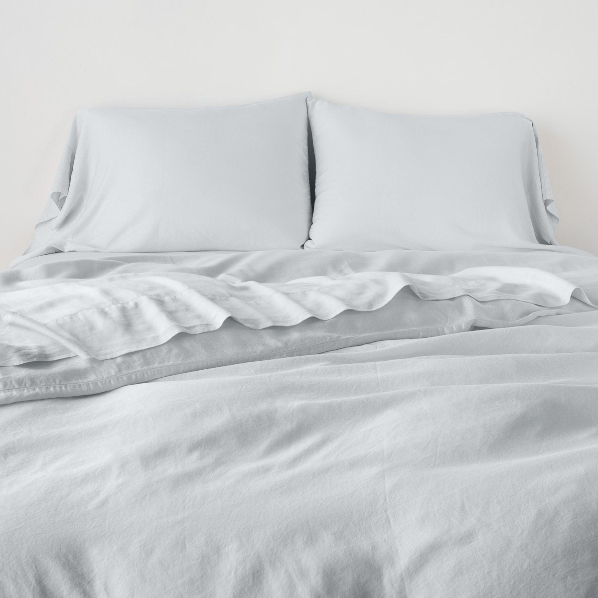 Cloud: duvet cover with matching sleeping pillows and sheeting against a white wall - end of bed view.
