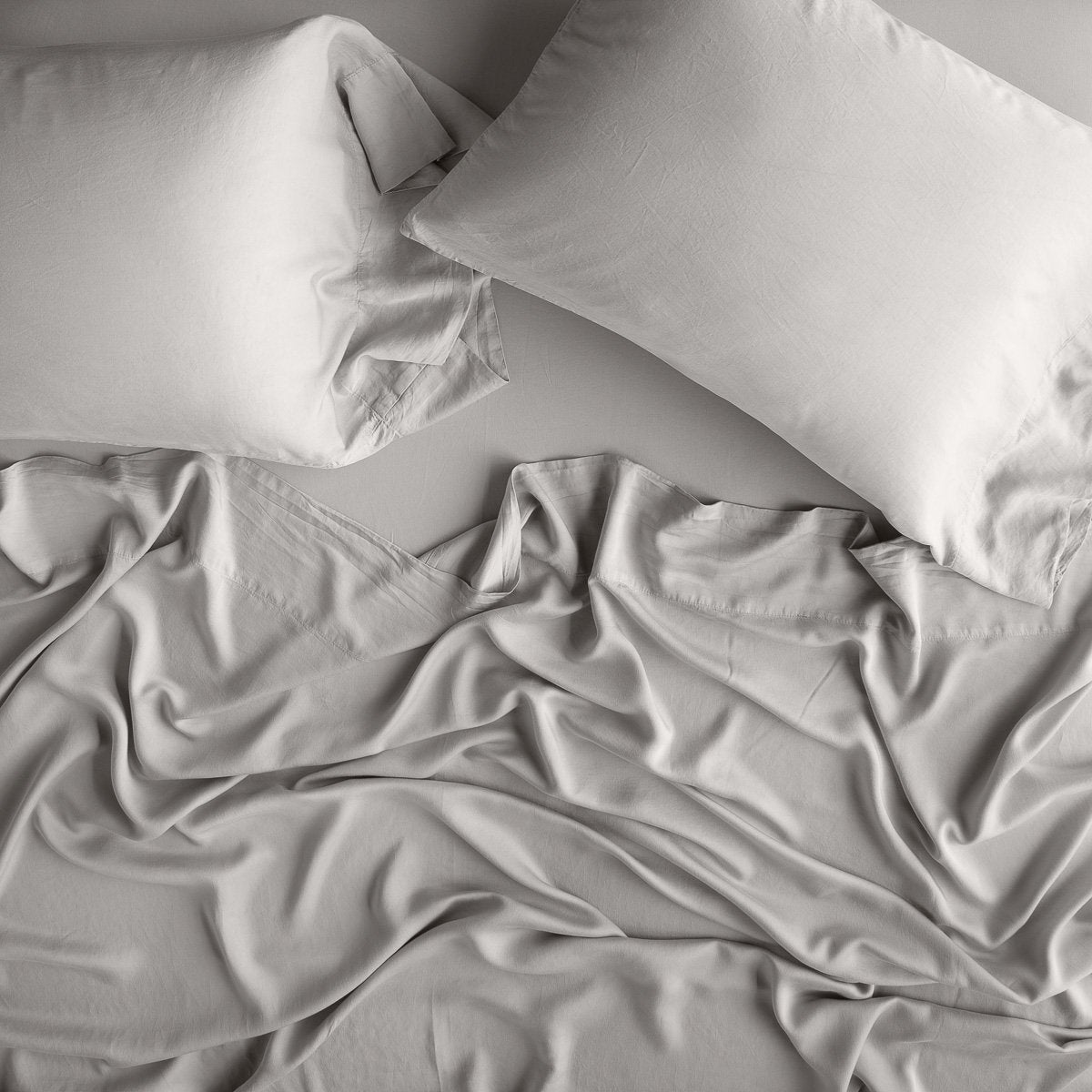 Fog: sleeping pillows laid flat over rumpled matching sheeting - overhead view.