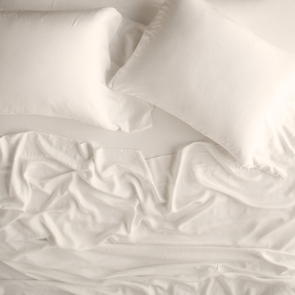 Parchment: sleeping pillows laid flat over rumpled matching sheeting - overhead view.