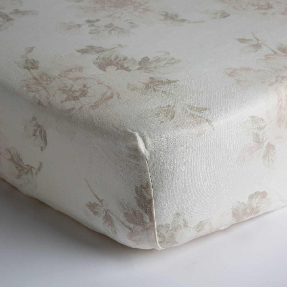 : a close up of the corner of the crib sheet to show the subtle floral pattern on midweight linen.
