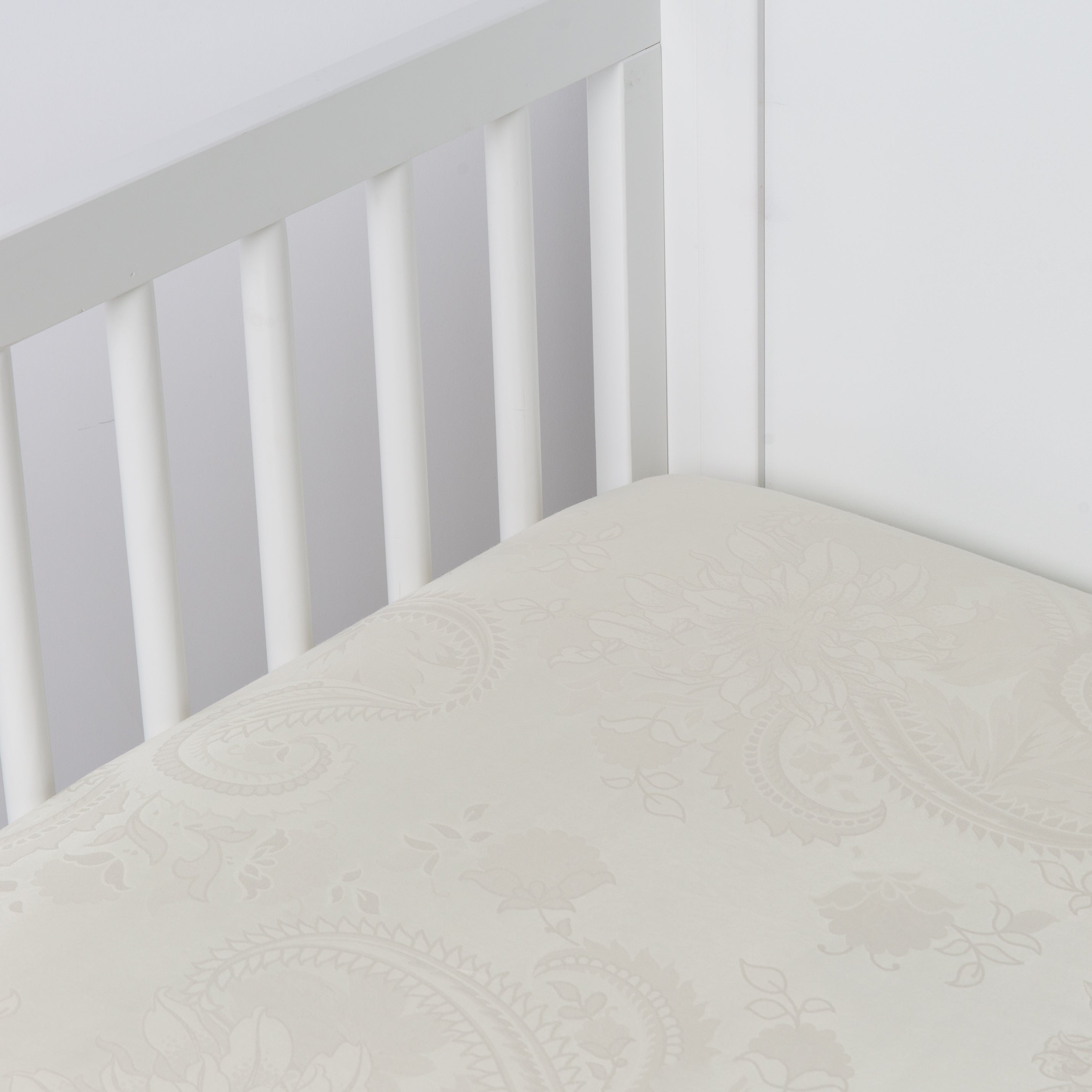 Parchment: a silk and tencel™ crib sheet shown slightly overhread and shot into the corner of a white crib.