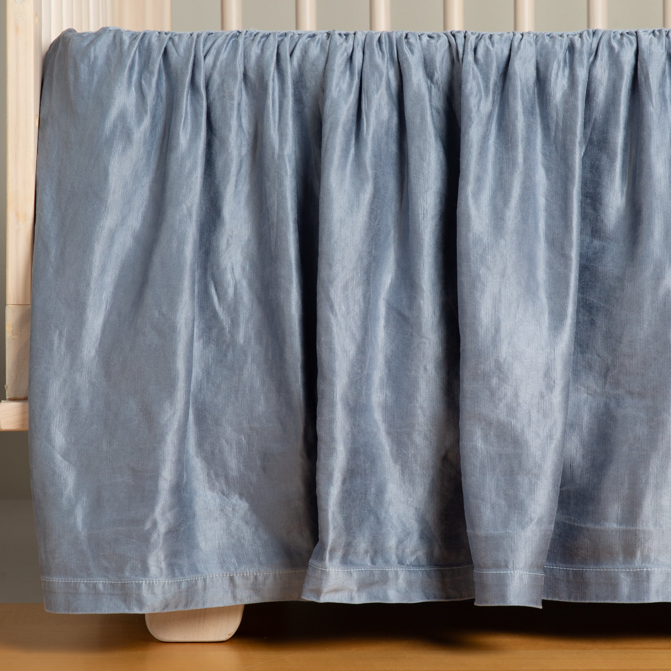Tahoe Blue: charmeuse crib skirt shown on a white crib against a white wall and medium wood floor.