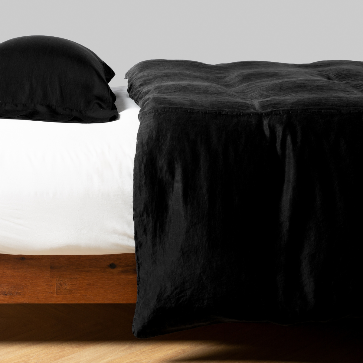 Corvino: side view of charmeuse duvet cover with matching pillowcase on white fitted sheet.