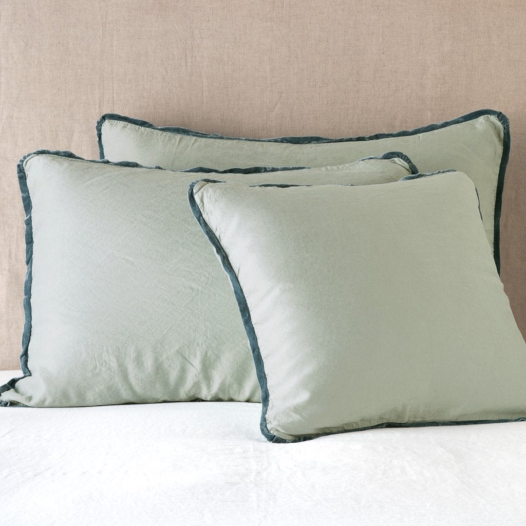 Eucalyptus: shams leaning upright on white sheeting against a neutral headboard.