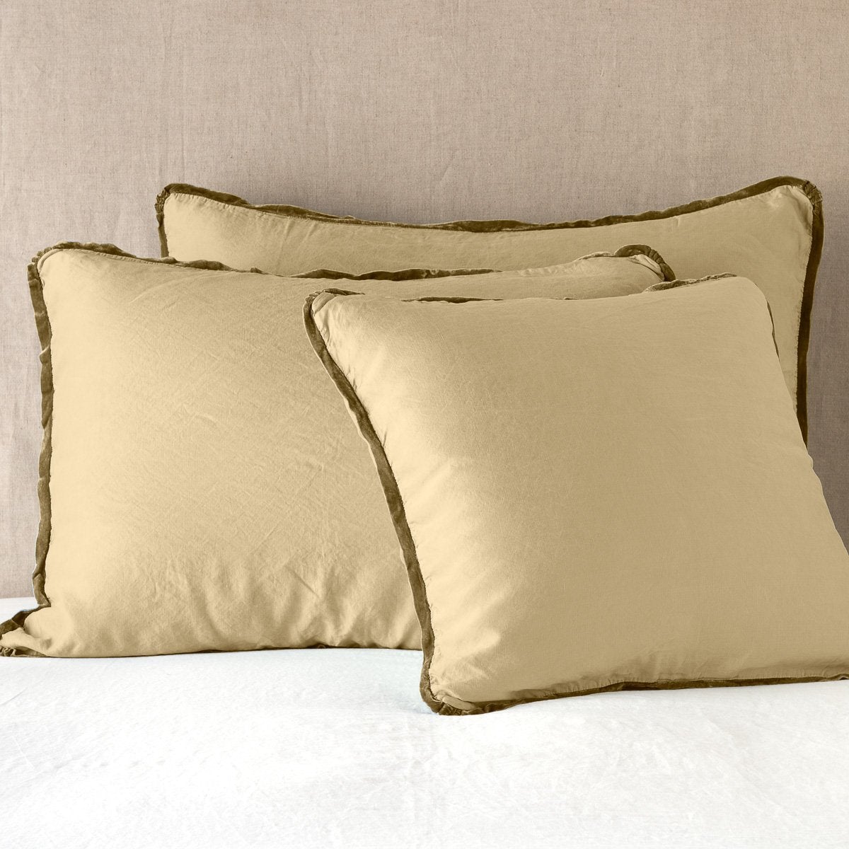 Honeycomb: shams leaning upright on white sheeting against a neutral headboard.