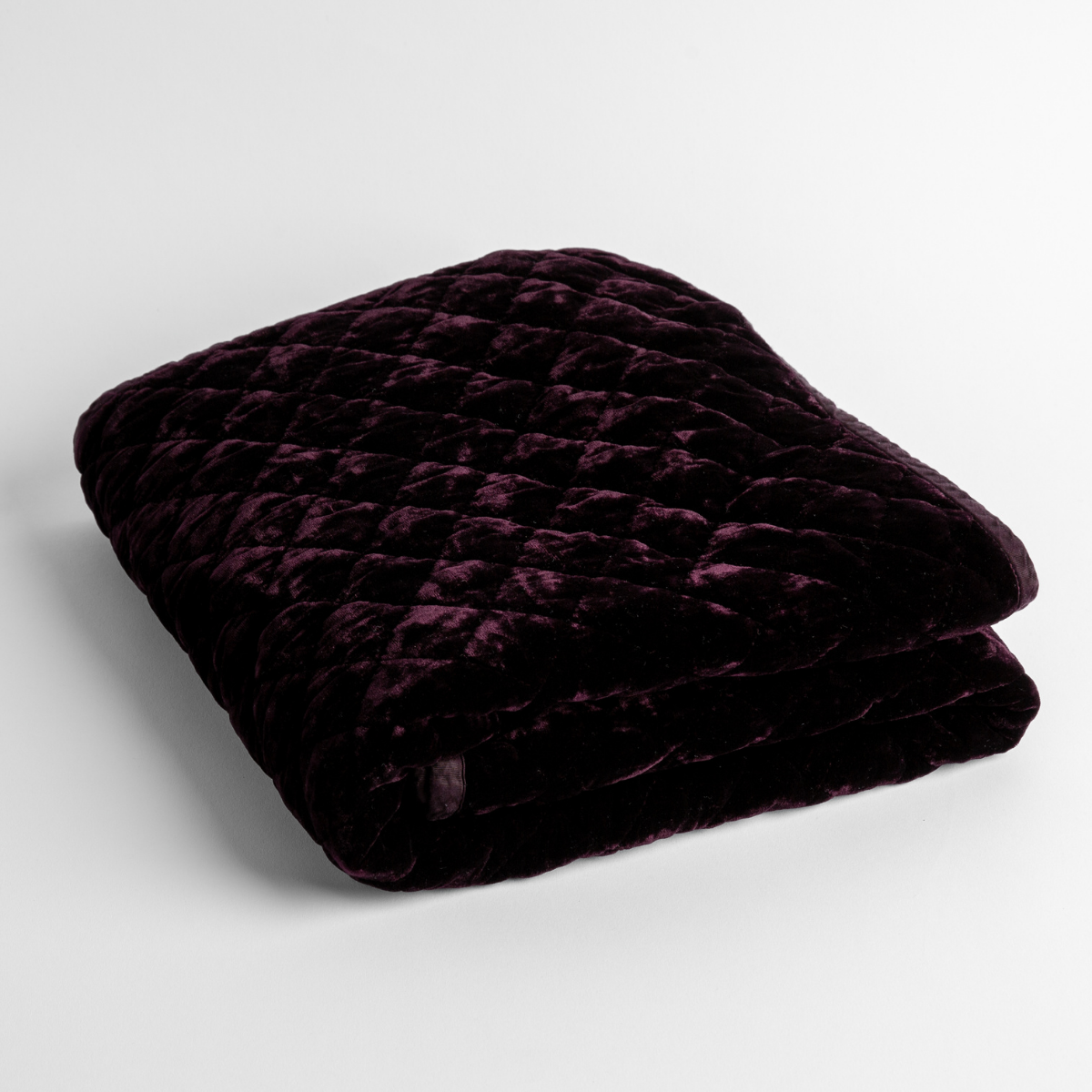 Fig: a folded quilted silk velvet baby blanket shown from overhead to showcase quilting pattern and texture.