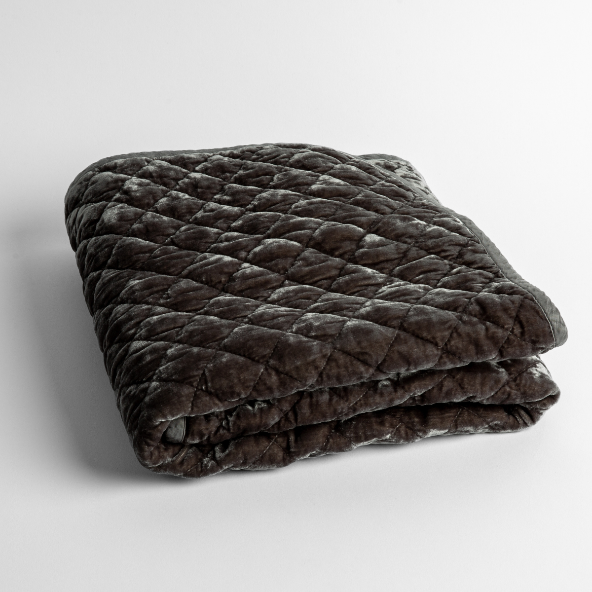 Moonlight: a folded quilted silk velvet baby blanket shown from overhead to showcase quilting pattern and texture.