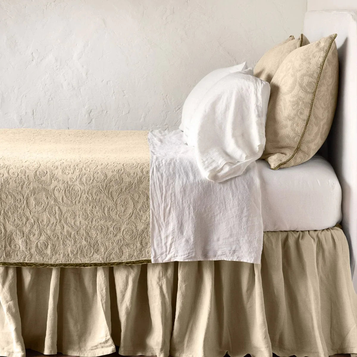 Honeycomb: The Adele coverlet in honeycomb, on a bed viewed from the side against a plain white wall. The bed is styled neatly with the coverlet folded back to reveal white sheets, bed skirt and pillows.