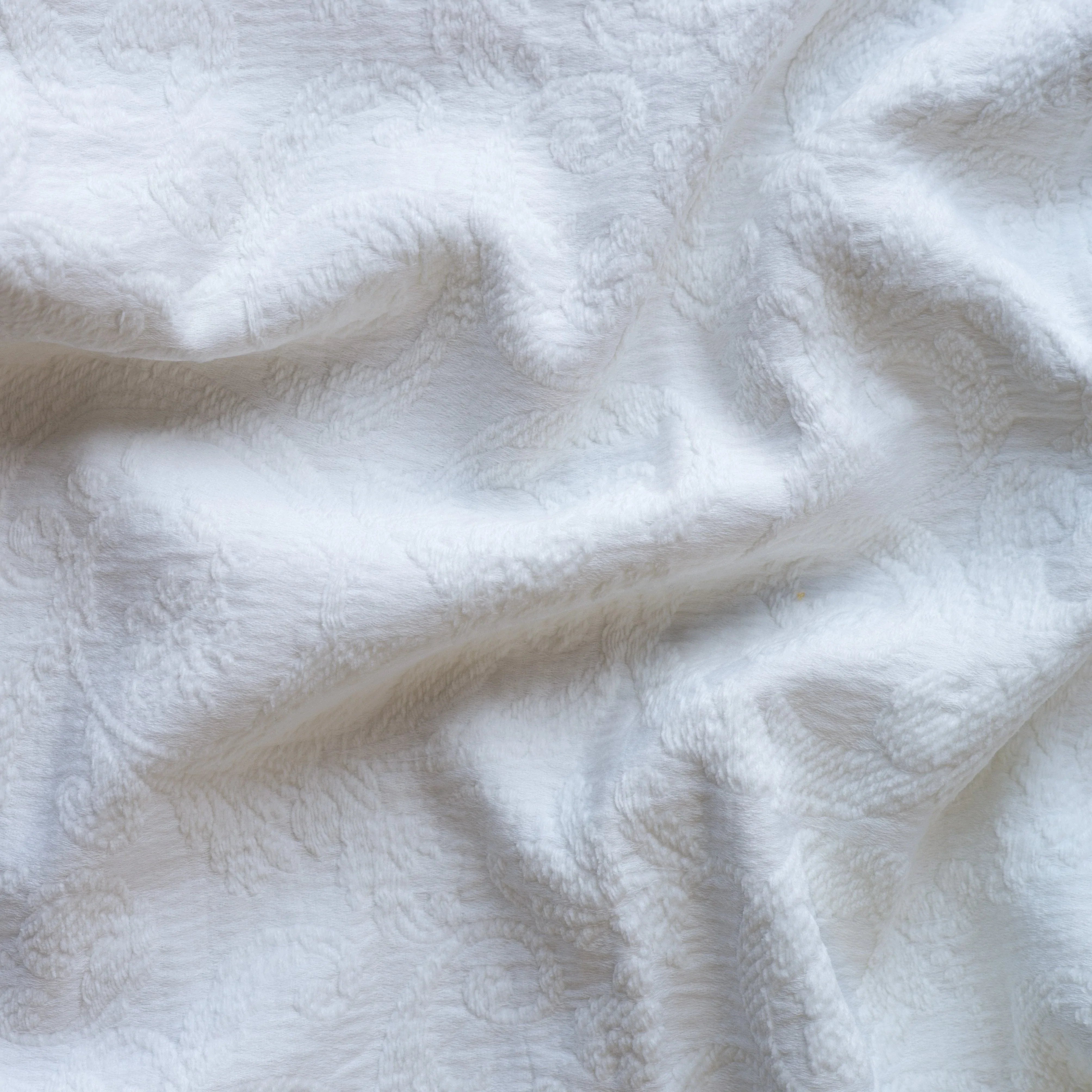 White: A close up of Adele fabric in white. The fabric is rumpled to show the cotton damask texture.