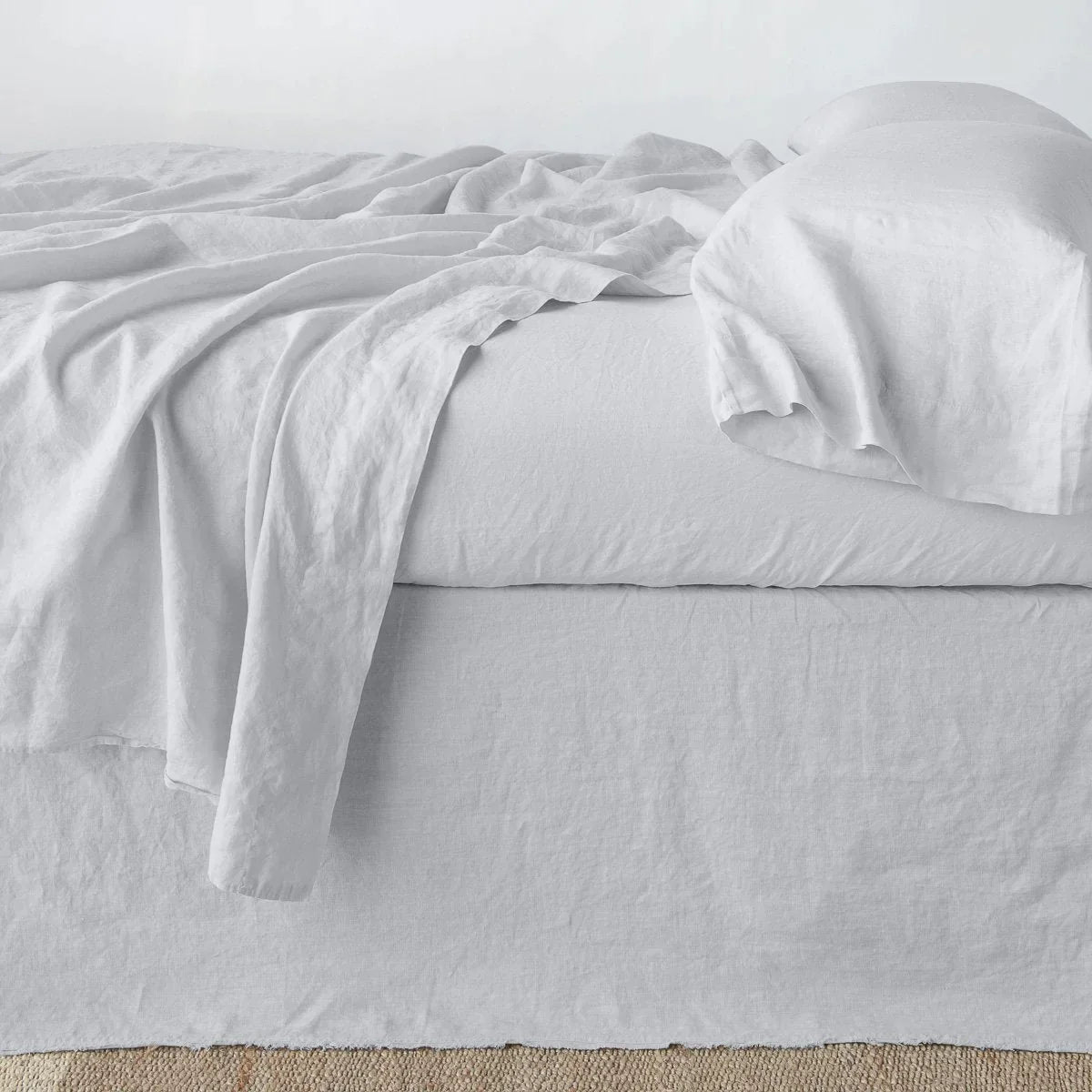 Sterling: Austin bed skirt in sterling shown from the side on a bed with monochromatic sheeting, highlighting its tailored, ungathered style.