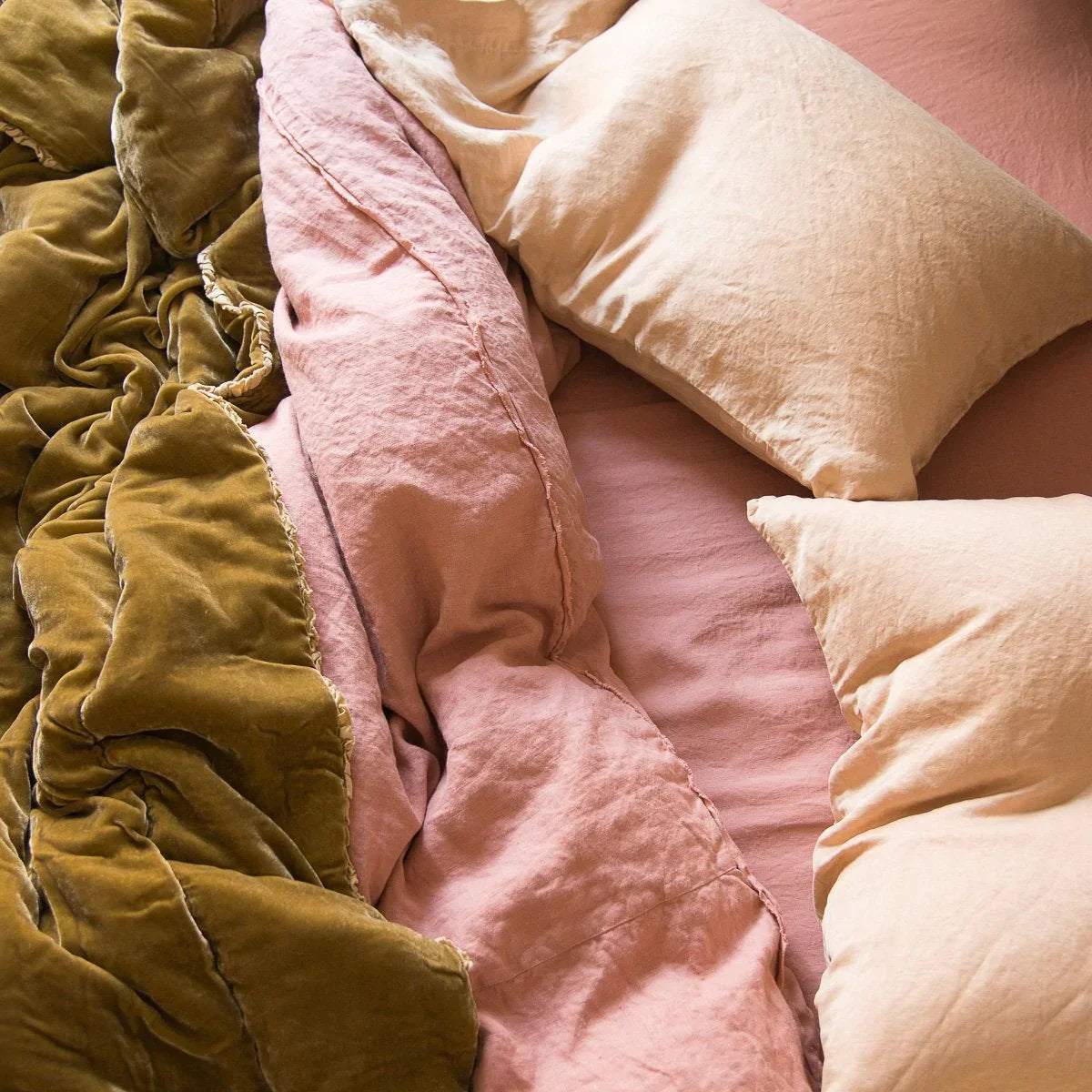 : Austin duvet cover shown rumpled from an overhead angle with silk velvet and silk charmeuse in pink and gold tones.
