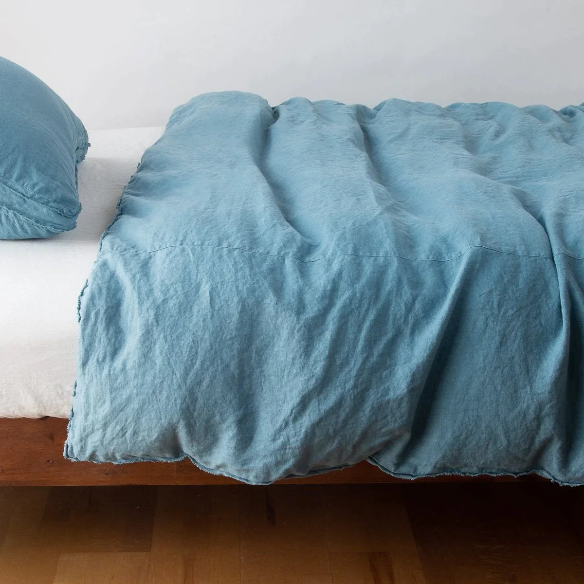 Cenote: Midweight linen duvet cover in cenote on a bed, side view.
