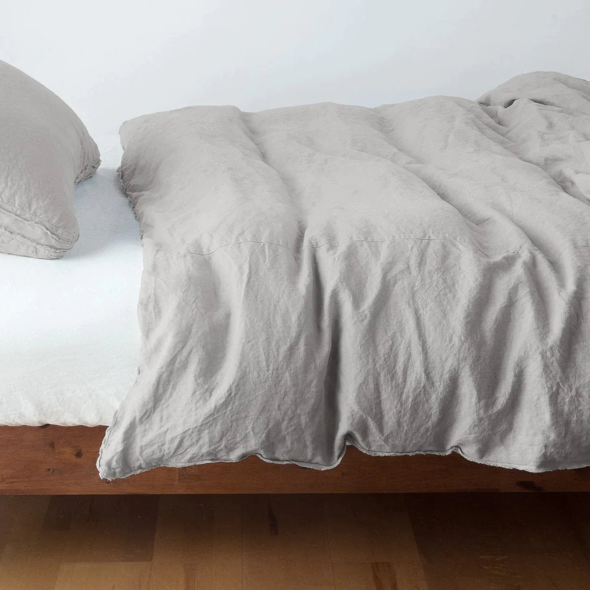 Fog: Midweight linen duvet cover in fog on a bed, side view.